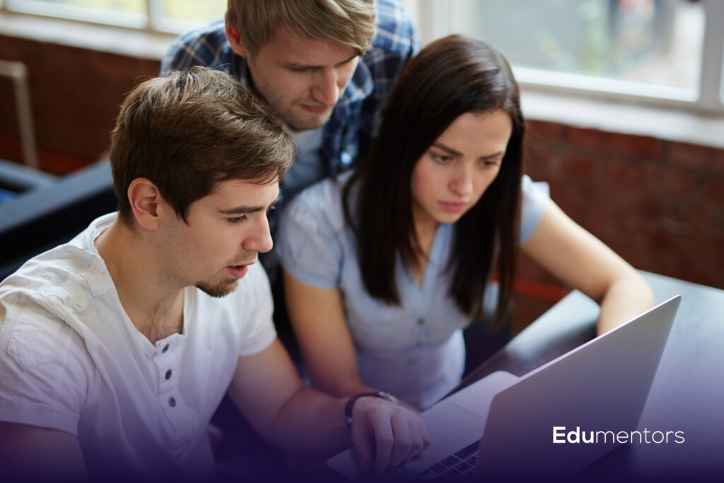 University students working together on a laptop while comparing Computer Science courses and study options.